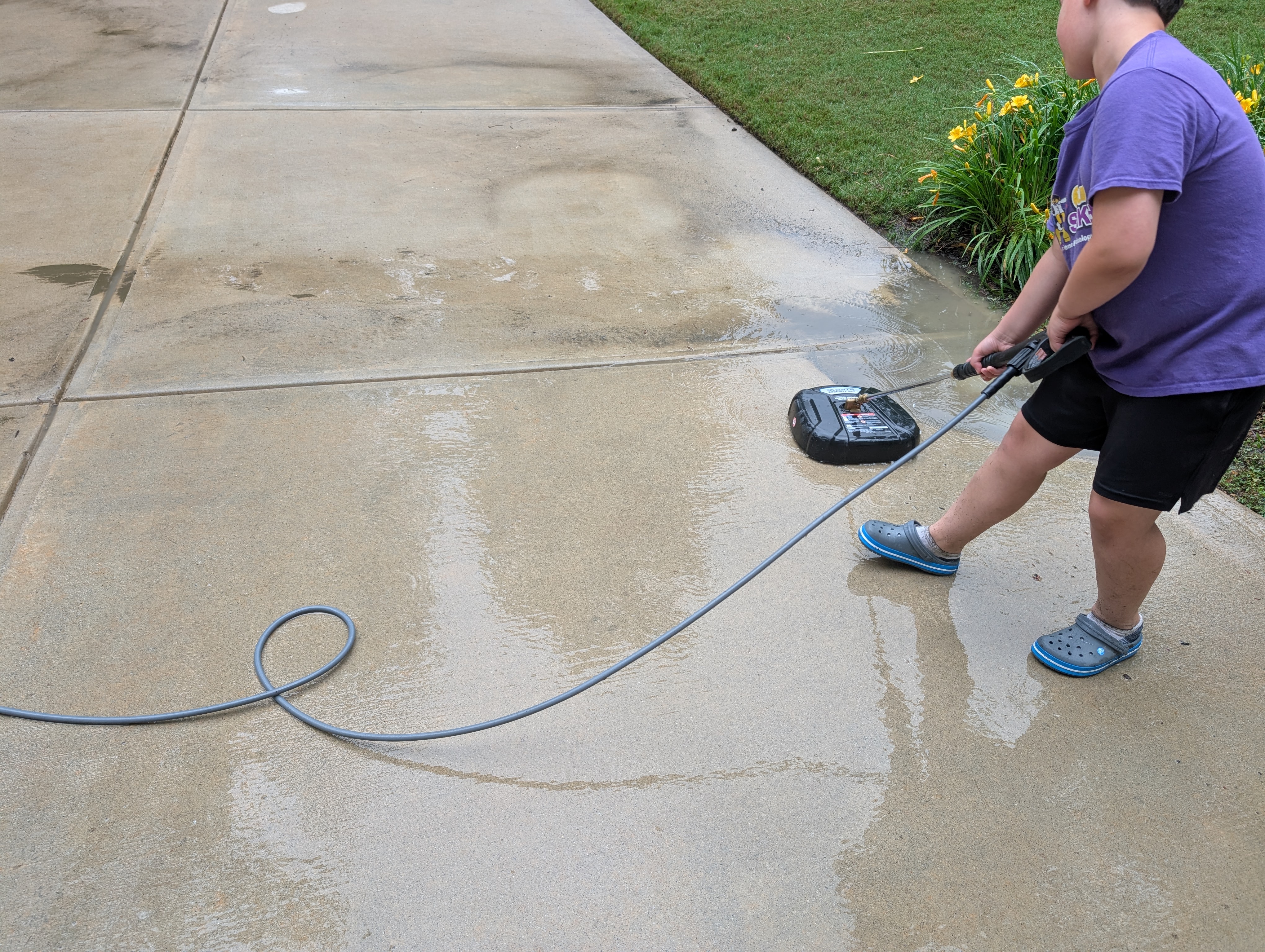 The Pressure Wash Kid using a surface cleaner on a residential driveway
